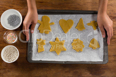 Man holding baking tray full of ginger bread cookies