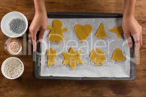 Man holding baking tray full of ginger bread cookies