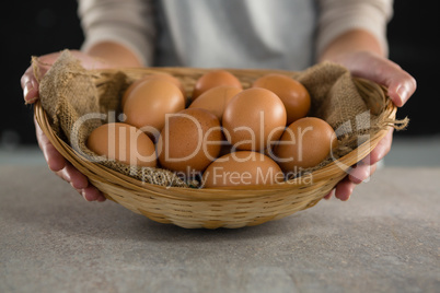 Woman holding basket with brown eggs