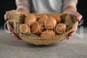 Woman holding basket with brown eggs