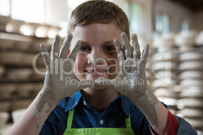 Boy showing clay hands in pottery shop