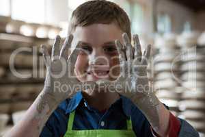 Boy showing clay hands in pottery shop