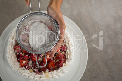 Woman icing sugar on tart