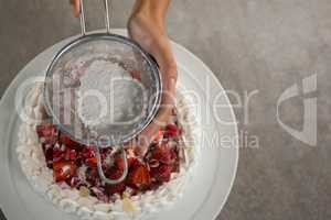 Woman icing sugar on tart
