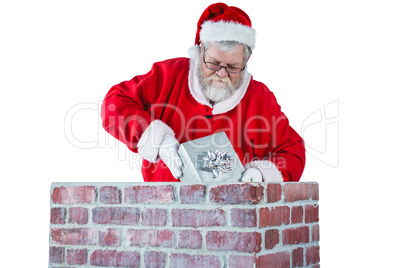 Santa claus placing gift box into a chimney