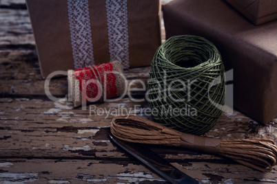 Gift boxes with wrapping material on wooden plank