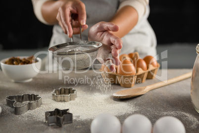 Woman staining flour in sieve