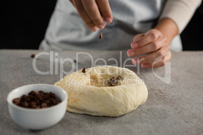 Woman adding chocolate chips into the dough