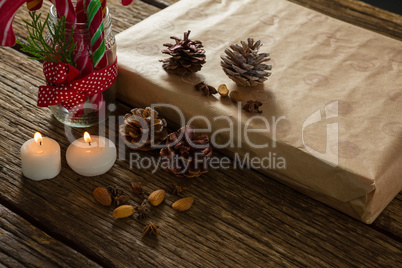 High angle view of illuminated candles with pine cones and gift box