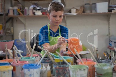 Boy painting a bowl in pottery shop