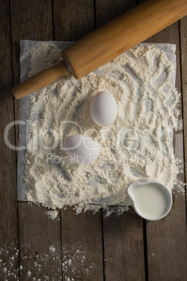 Flour, eggs and rolling pin placed over butter paper on a table