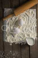 Flour, eggs and rolling pin placed over butter paper on a table
