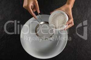 Woman sieving flour into the bowl