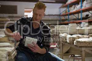 Male potter using digital tablet in pottery workshop