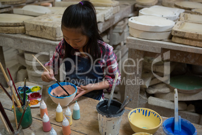 Attentive girl painting a bowl