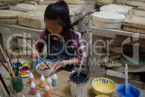 Attentive girl painting a bowl