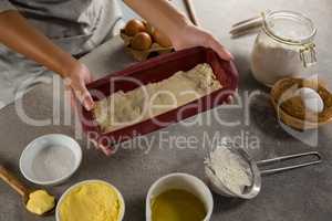 Woman preparing dough surrounded with various ingredients