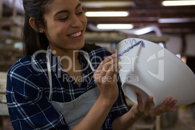 Female potter decorating bowl with paint brush