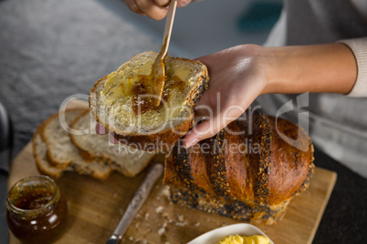 Woman applying jam over multigrain bread slice