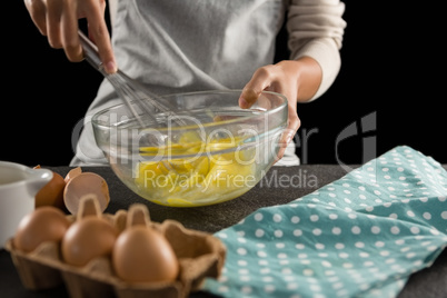 Woman beating eggs with a whisk in a bowl