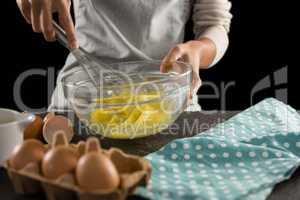 Woman beating eggs with a whisk in a bowl