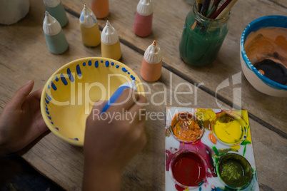 Hand of girl painting bowl
