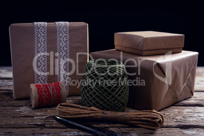 Gift boxes with wrapping material on wooden plank