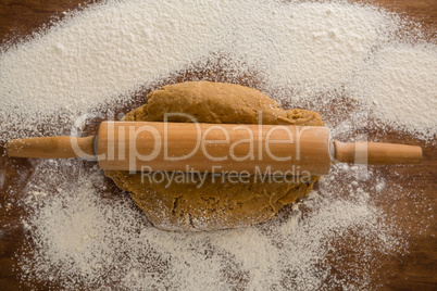 Flattening dough with rolling pin with sprinkled over flour on a wooden table