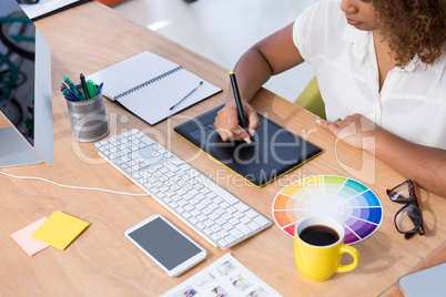 Female executive working over graphic tablet at her desk