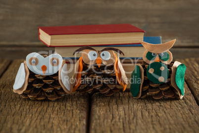 Owl decorated with pine cone and book stack on wooden table