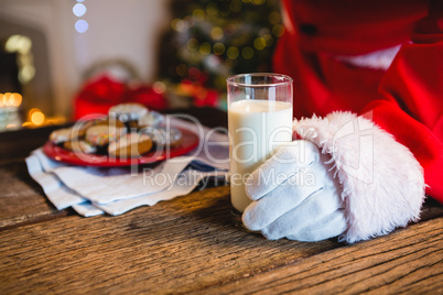 Mid-section of Santa Claus holding a glass of milk