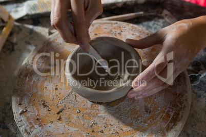 Hands of female potter molding a bowl with hand tool