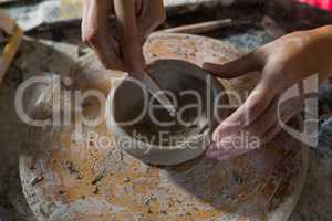 Hands of female potter molding a bowl with hand tool