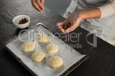 Woman adding dry fruits over unbaked cookie dough
