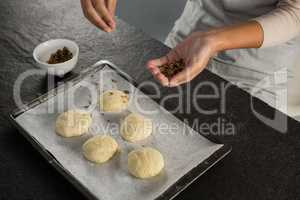 Woman adding dry fruits over unbaked cookie dough