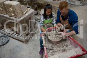 Male potter assisting girl in molding a clay