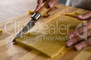 Woman slicing dough on chopping board