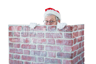 Santa claus hiding behind a chimney