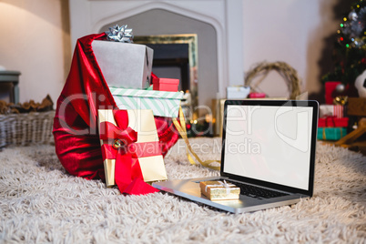 Gift sack, gift and laptop placed together on rug