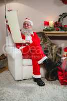 Santa Claus reading scroll in living room