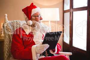 Santa claus using digital tablet in living room during christmas time