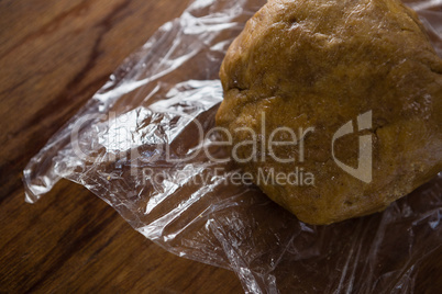 Dough placed over plastic wrap on a wooden table