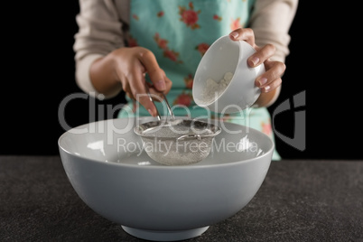 Woman sieving flour into the bowl