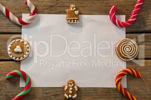 Overhead view of candy canes with gingerbread cookies and paper arranged on table