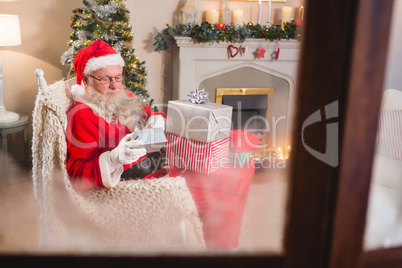 Santa claus looking at gift boxes in living room at home