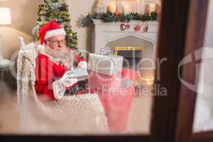 Santa claus looking at gift boxes in living room at home