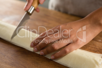 Woman slicing dough on chopping board