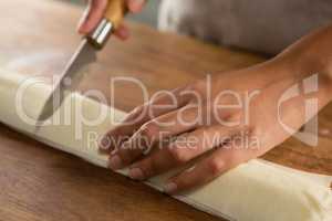 Woman slicing dough on chopping board