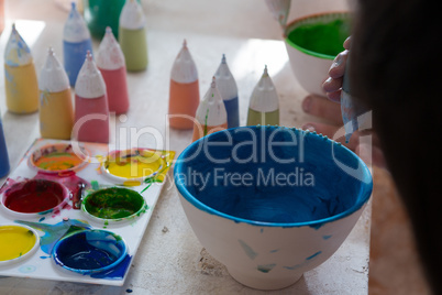 Girl decorating bowl with paint