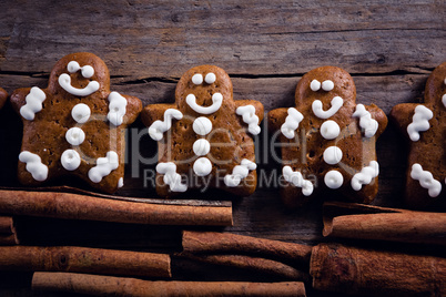 Gingerbread cookies and cinnamon sticks arranged on wooden plank